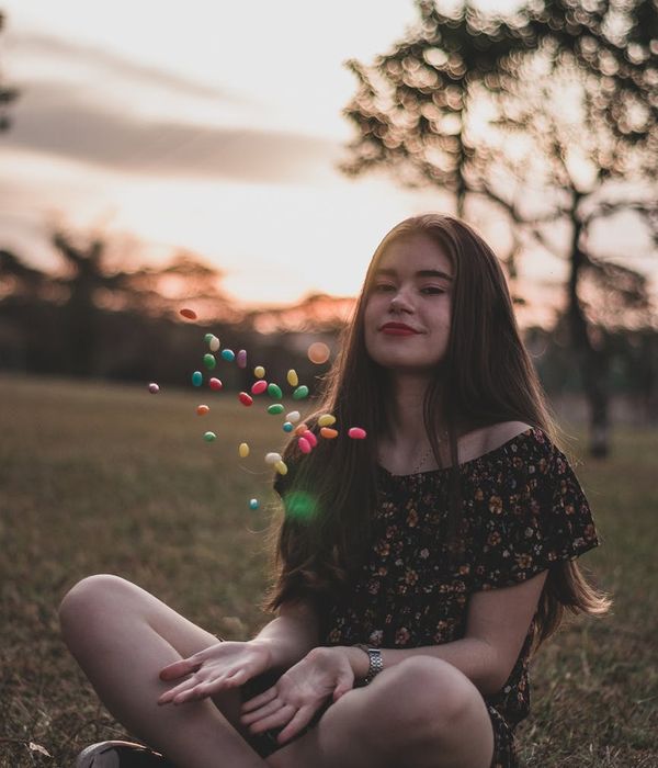A person smiling and stretching outdoors in a park at sunrise.